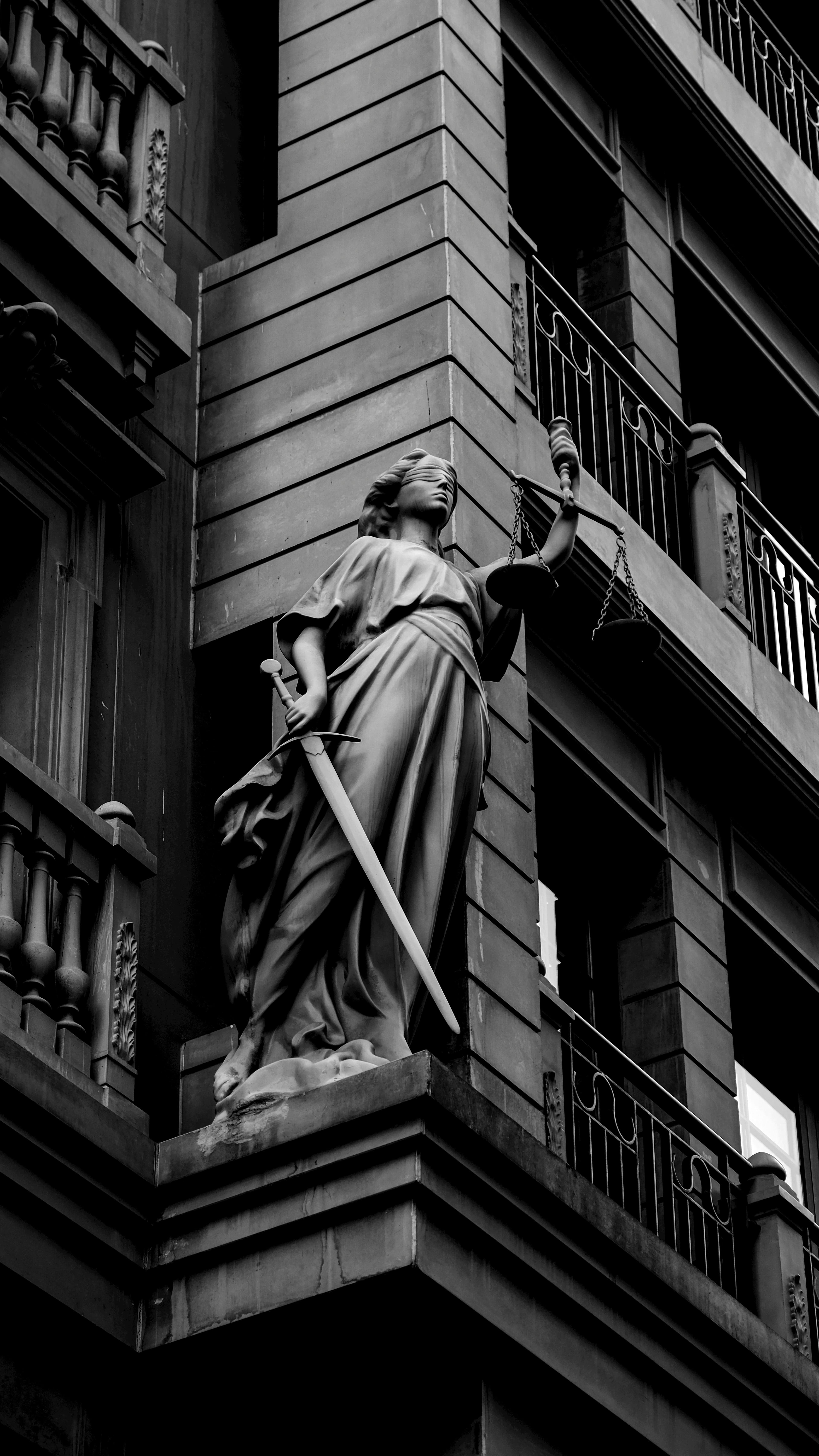 Estátua da Justiça segurando a balança e a espada na fachada de um edifício clássico